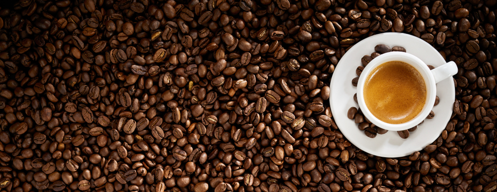 Latar belakang biji kopi panggang segar dengan secangkir espresso panas berbusa